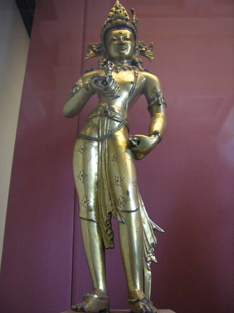 British Museum Top 20 Buddhism 16-1 Vajrasattva 16. Vajrasattva � Nepal, 15C AD, 52cm high. The gilded bronze standing figure holds the vajra and bell in his hands, has elaborate jewelry, and is inset with semi-precious stones. In Vajrasattva's crown is the seated figure of the Akshobhya, the Tathagata Meditation Buddha of the East.